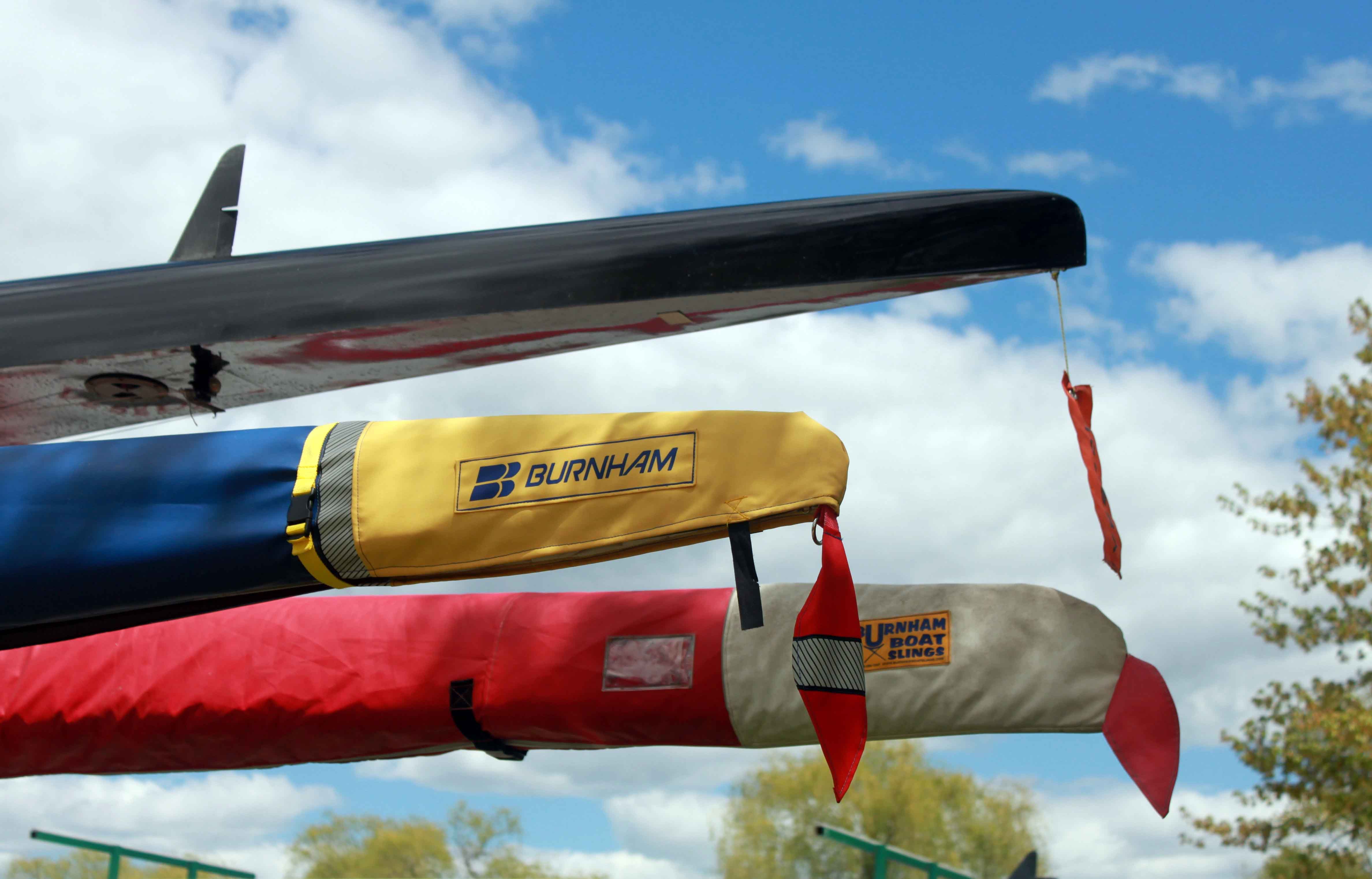 The sterns of 3 racing shells with a blue sky behind them.