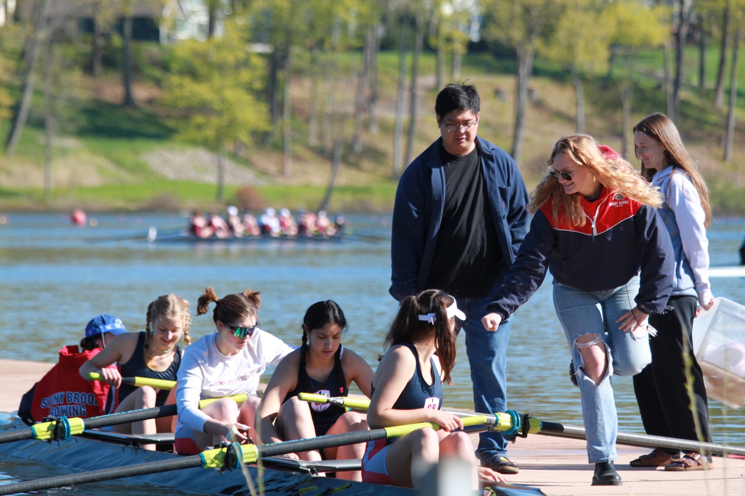 Women's Varsity 4 preparing to launch with their coaches on the dock.